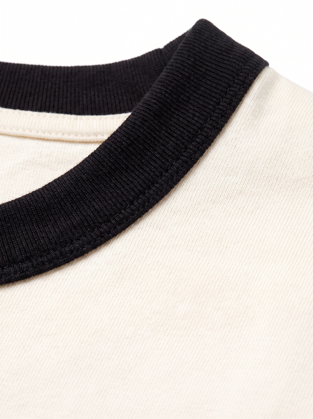 Close up of black contrast ribbed collar on cream tee