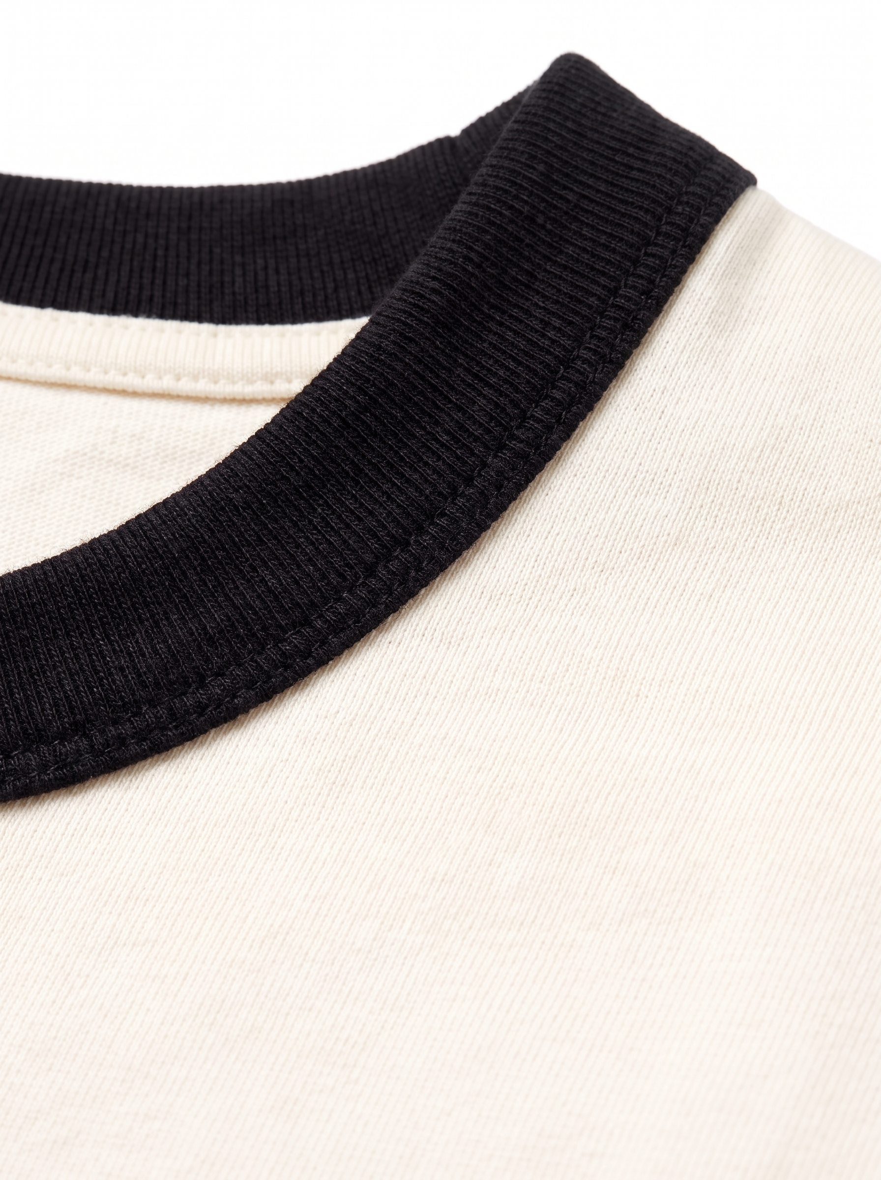 Close up of black contrast ribbed collar on cream tee