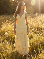 Woman wearing the pale yellow V-neck tiered frill maxi dress in a sunlit meadow