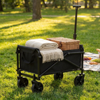 Collapsible outdoor wagon on park grass loaded with a blanket and picnic basket