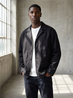 Black canvas chore jacket with patch pockets in a bright studio space
