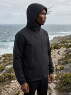Black half zip hooded anorak pullover jacket on a coastal path