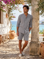 Man wearing a grey linen two-piece summer set in a seaside villa courtyard