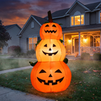 Inflatable stacked pumpkins lit up in front of a house