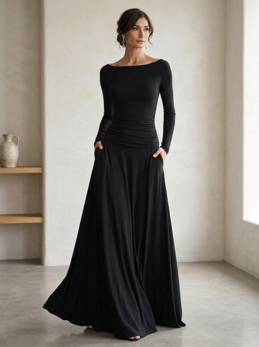 Model wearing a black long sleeve maxi dress in soft draping fabric in a modern interior