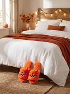Pumpkin monster slippers at the foot of a bed