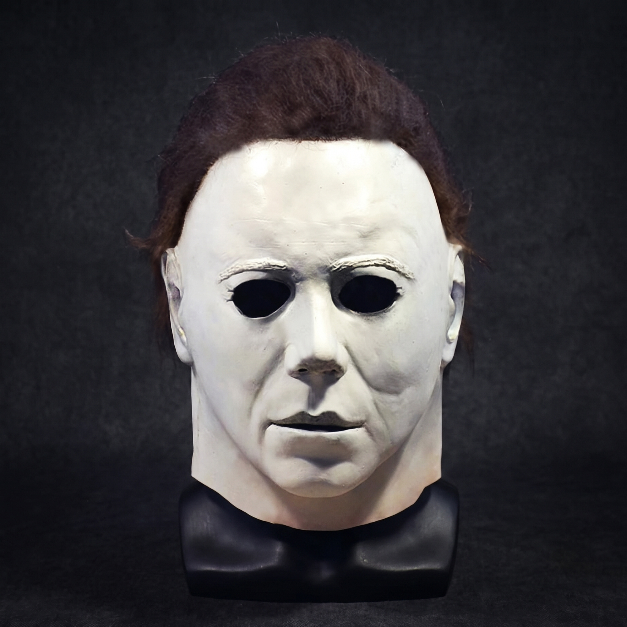Latex horror mask displayed on a black mannequin head stand