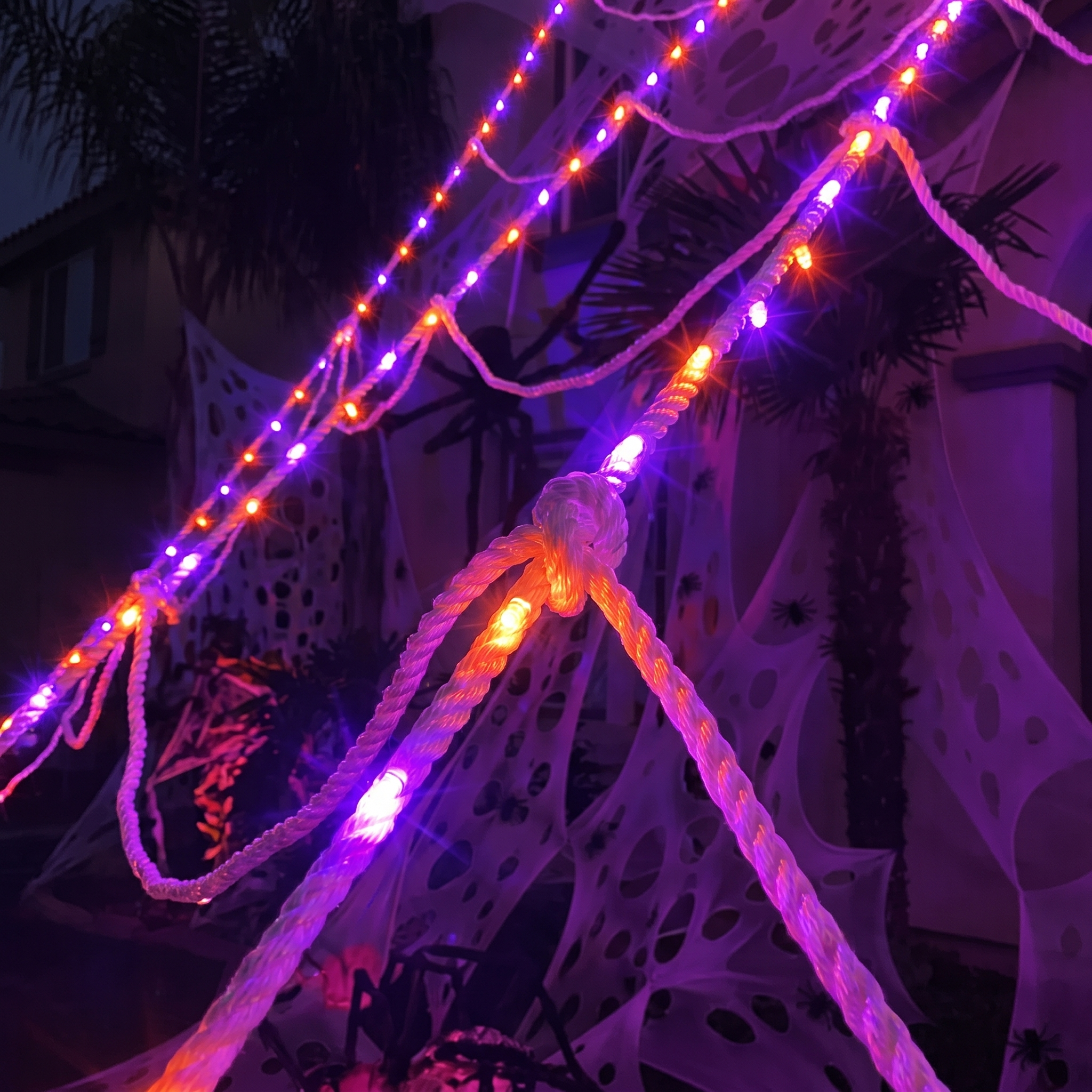 Close-up of glowing purple and orange LED strands on the rope web