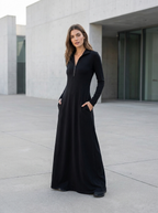 Woman wearing the black maxi dress with a half-zip stand collar on a modern concrete plaza